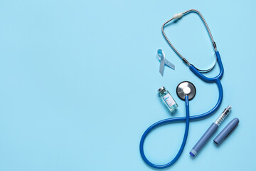 Awareness ribbon with insulin, stethoscope and lancet pen on blue background. Diabetes concept
