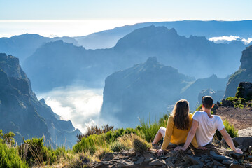 Tourist couple enjoys the picturesque view from the mountain top of a volcanic island on a sunny...