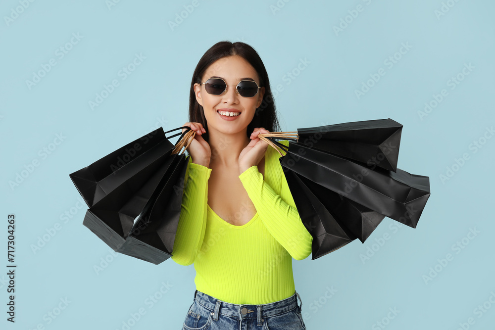 Sticker beautiful young asian woman with shopping bags on blue background. black friday sale