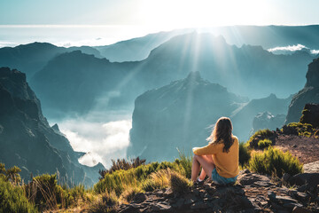 Female tourist enjoys the panoramicview from the mountain top of a volcanic island on a sunny summer afternoon. Pico do Arieiro, Madeira Island, Portugal, Europe.