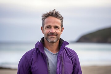 Portrait of handsome middle aged man smiling at camera on the beach