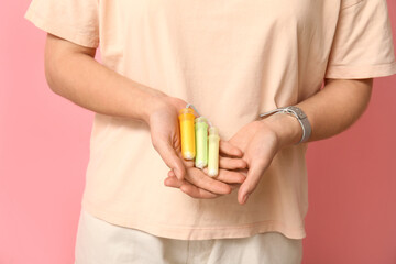 Young woman with tampons on pink background, closeup