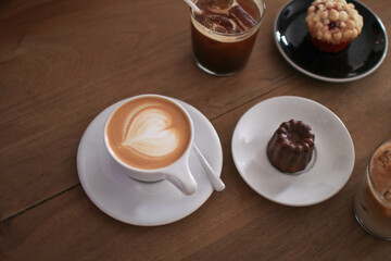 Hot Latte espresso coffee with heart shape latte art in white ceramic cup serve with bakery on wooden table.  Morning breakfast.