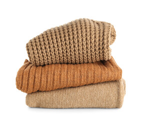 Stack of beige stylish sweaters on white background