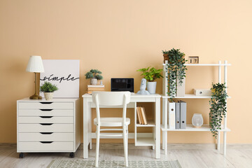 Interior of stylish office with workplace, shelf unit and drawers