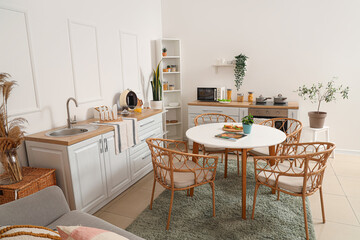 Interior of light kitchen with green plants, counters and dining table