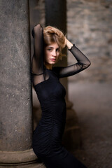 Fototapeta na wymiar Girl in black dress leaning on a column