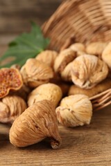 Overturned wicker basket and dried figs on wooden table, closeup