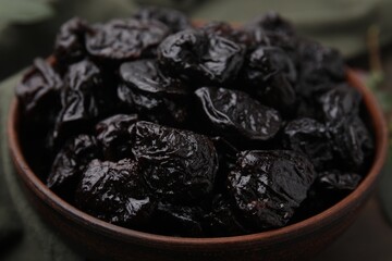 Sweet dried prunes in bowl on table, closeup