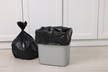 Plastic garbage bag and trash can indoors. Space for text