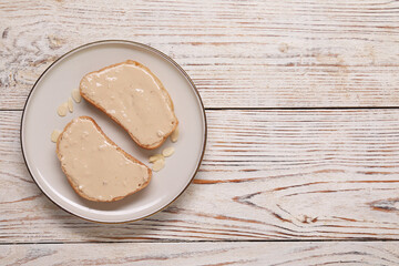 Toasts with tasty nut butter and almond flakes on light wooden table, top view. Space for text