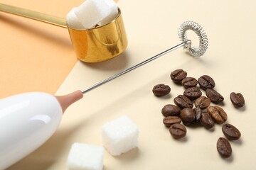 Fototapeta premium Milk frother wand, coffee beans and sugar cubes on color background, closeup