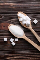 Spoons with different types of white sugar on wooden table, flat lay