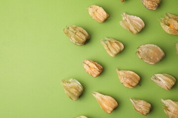 Ripe physalis fruits with calyxes on light green table, flat lay. Space for text