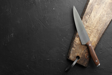 One sharp knife and board on dark textured table, top view. Space for text