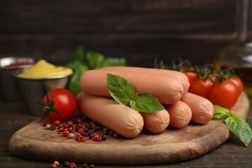 Delicious boiled sausages, tomatoes, basil and peppercorns on wooden table, closeup