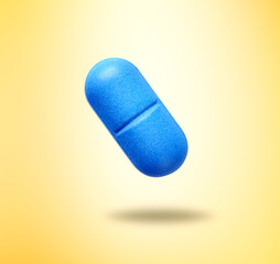 Blue vitamin pill in air on yellow gradient background
