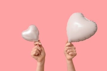 Woman with air balloons in shape of heart on pink background. Valentine's Day celebration