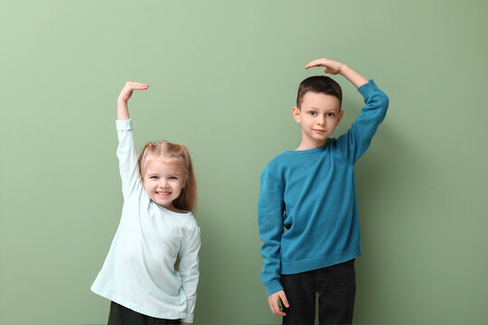 Cute little children measuring height on green background