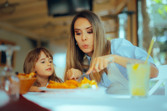 Woman Cutting Food in Small Pieces for her Daughter. Mom and toddler girl bonding over having lunch together 
