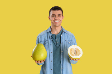 Young man with pomelo on yellow background