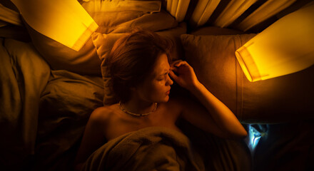 young woman lies in bed in warm light and cries, illness sleep disorder and insomnia, mental illness