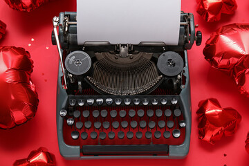Vintage typewriter and heart-shaped air balloons for Valentine's day on red background