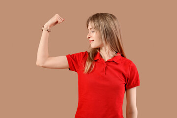 Beautiful young happy woman showing muscles on beige background. Women history month