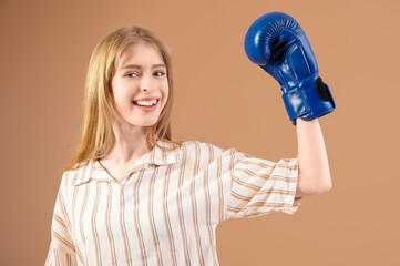 Beautiful young happy woman in boxing gloves on beige background. Women history month