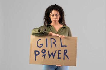 Beautiful young African-American woman holding paper with text GIRL POWER on grey background. Women...