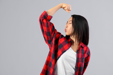 Beautiful young Asian woman showing muscles and blowing kiss on grey background. Women history month