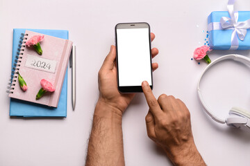 Male hands with modern mobile phone, notebooks and headphones on white background