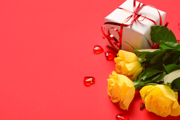 Beautiful rose flowers and gift box for Valentine's Day celebration on red background