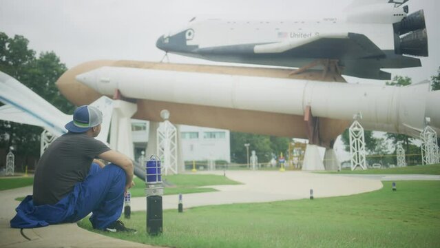 Man waiting in grass staring up at epic space shuttle