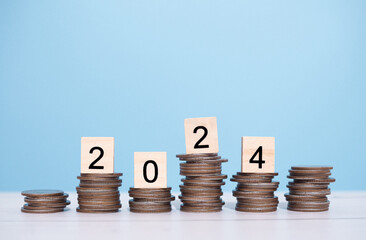 Wooden block with number 2024 on stack of coins. The concept of saving money for business...
