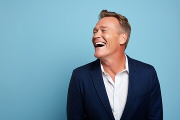 Handsome middle aged man laughing and looking up on blue background