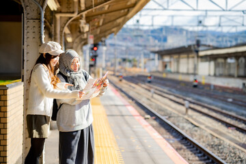 woman girl tourist Two Asian friends but different religions,They were looking at information about preparing to board the train at the train station,She is traveling in Japan. with fun, Japan travel 