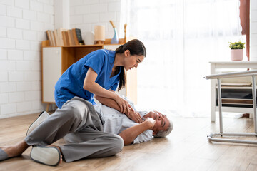 Asian caregiver helping senior male from falling on the ground at home. 
