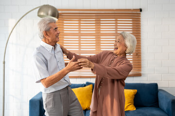 Obraz premium Asian active senior couple enjoy dance together in living room at home. 