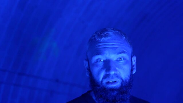 Young stylish man singing rap song on camera. Media. Hip hop singer in neon lighting at night club.