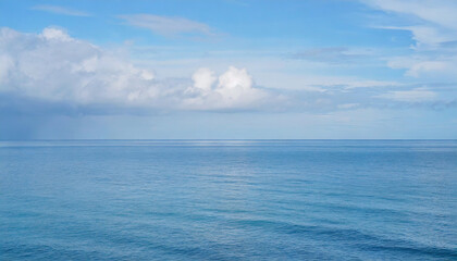 Obraz premium Tranquil Seascape under a Clear Blue Sky with Fluffy Clouds on a Sunny Summer Day