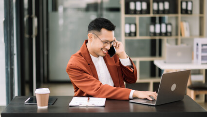 Young attractive man using laptop and tablet while sitting at her working place. Concentrated at work.