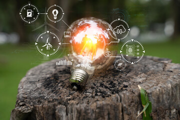 Holding a light bulb against nature on green leaf with energy source icon for renewable and...