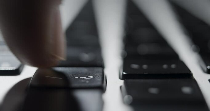 Extreme Close-up of Fingertip Pressing Laptop Question Mark Key