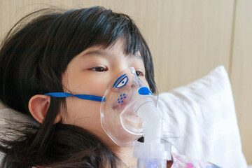 Sick little asian girl inhalation with nebulizer for respiratory treatment