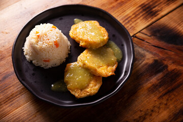 Cutlets of shredded chicken meat fried in batter egg, in Mexico known as Tortitas de Pollo, bathed with green sauce and accompanied by rice. Traditional and very popular homemade recipe in Mexico.