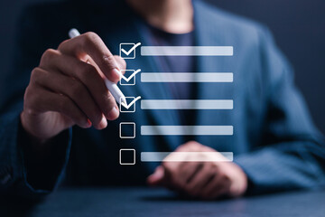 Checklist concept. Businessman use pen Checking mark on checkboxes for business performance monitoring and evaluation.