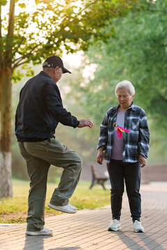 An elderly partner who kicks shuttlecock in the park