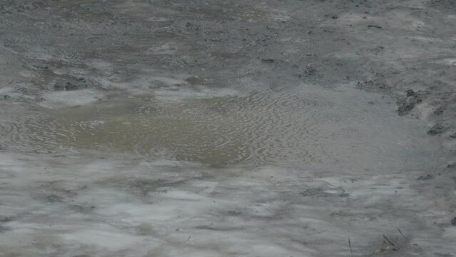 Raining in ice gravel road pothole in winter slow motion