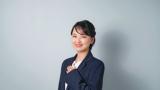 胸に手を当てるビジネススーツを着た女性